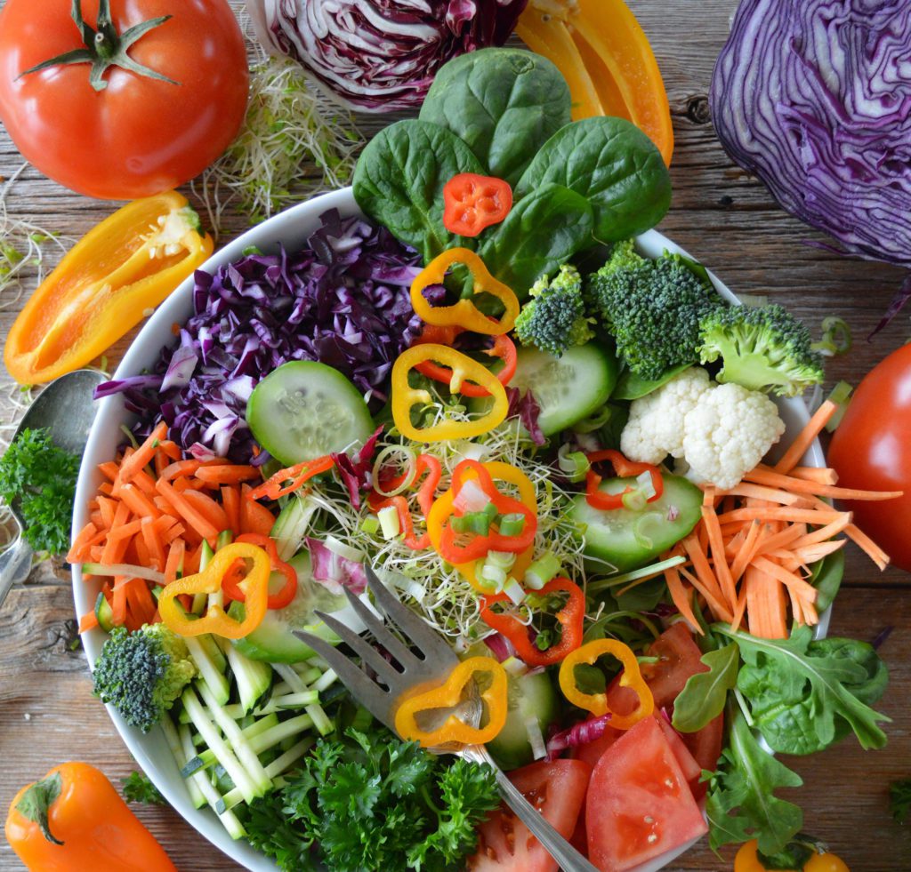 Brightly coloured, freshly sliced vegetables and salad in a bowl with a fork