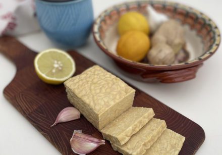 Tempeh sliced on a wooden board with lemon and garlic