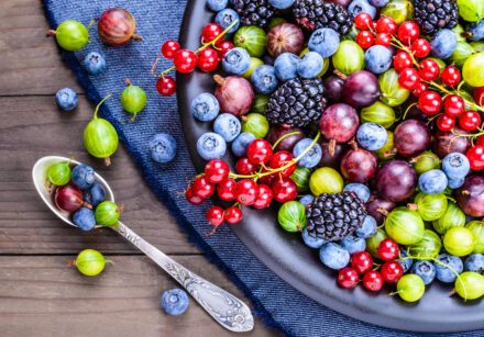 Different types of berries on a plate with a spoon